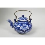 A small Chinese blue and white porcelain teapot with floral decoration and metal handle