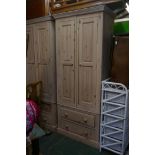 A whitewashed pine two door wardrobe with fielded panels over two long drawers, in two sections, 36"