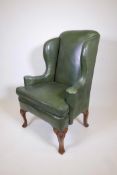 A Georgian style leather wing back armchair with scroll arms, 46½" high