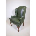 A Georgian style leather wing back armchair with scroll arms, 46½" high
