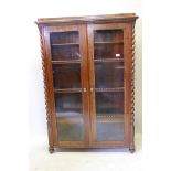 A C19th Dutch mahogany two door display cabinet, with barleytwist moulded decoration and canted