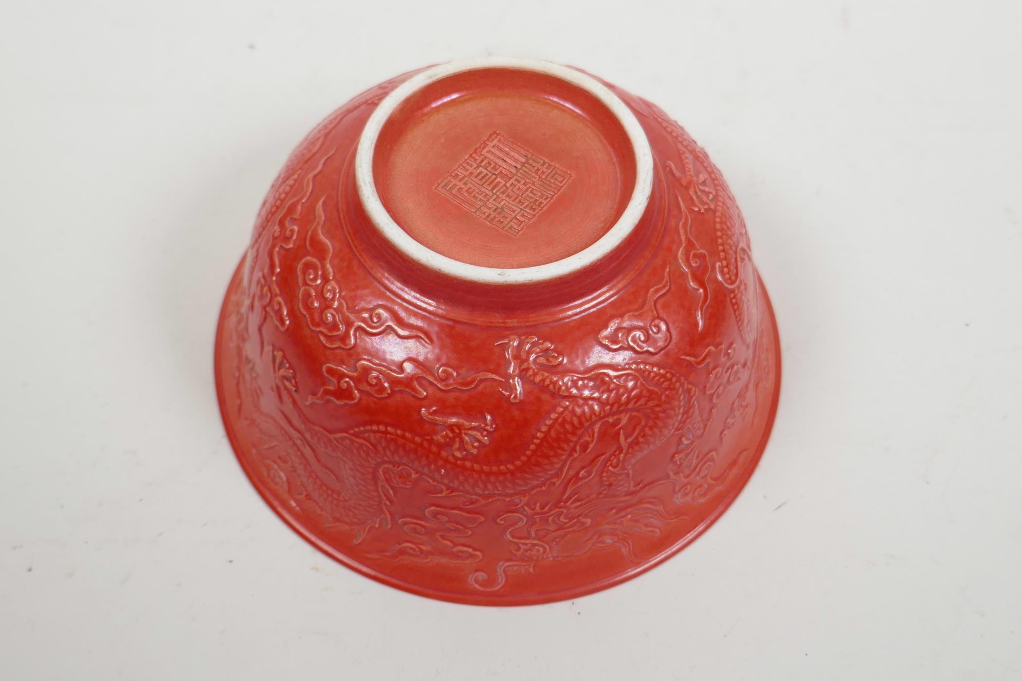 A Chinese red ground porcelain rice bowl with raised dragon decoration, impressed seal mark to base, - Image 2 of 4