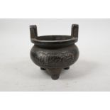 A Chinese bronze two handled censer on tripod feet with script decoration, 4 character mark to base,
