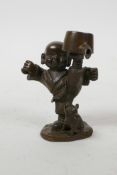 An Oriental bronzed metal figure of a boy practising martial arts and a piglet, impressed mark to
