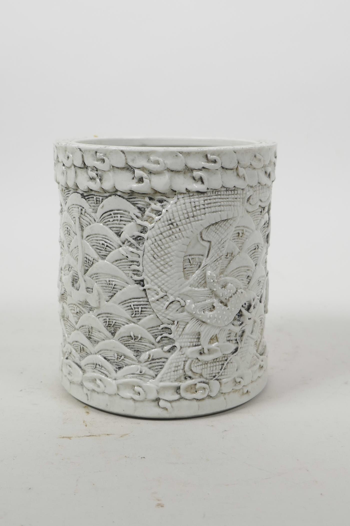 A Chinese moulded porcelain brush pot with raised decoration of dragons above water, impressed - Image 3 of 5