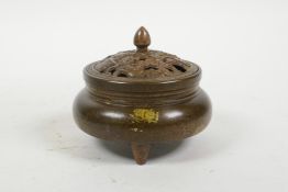 A Chinese gilt splash bronze censer and cover on tripod feet, with pierced waterfowl and lotus