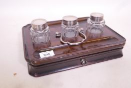 A Georgian mahogany desk stand with dished top and cut corners, fitted with glass inkwells and