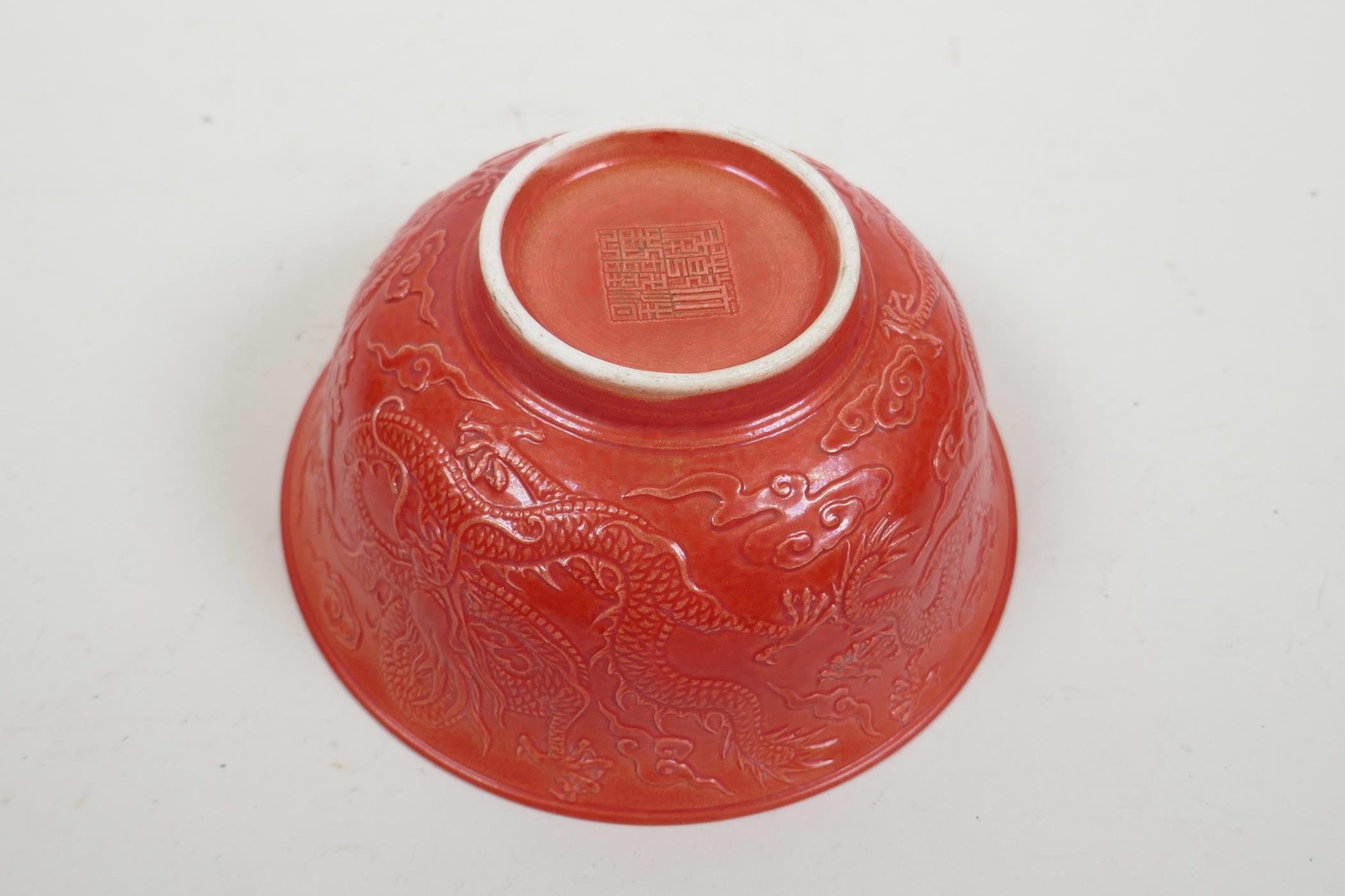 A Chinese red ground porcelain rice bowl with raised dragon decoration, impressed seal mark to base, - Image 3 of 4