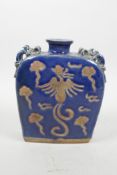 A Chinese blue glazed pottery flask with four dragon shaped handles and chased phoenix decoration,