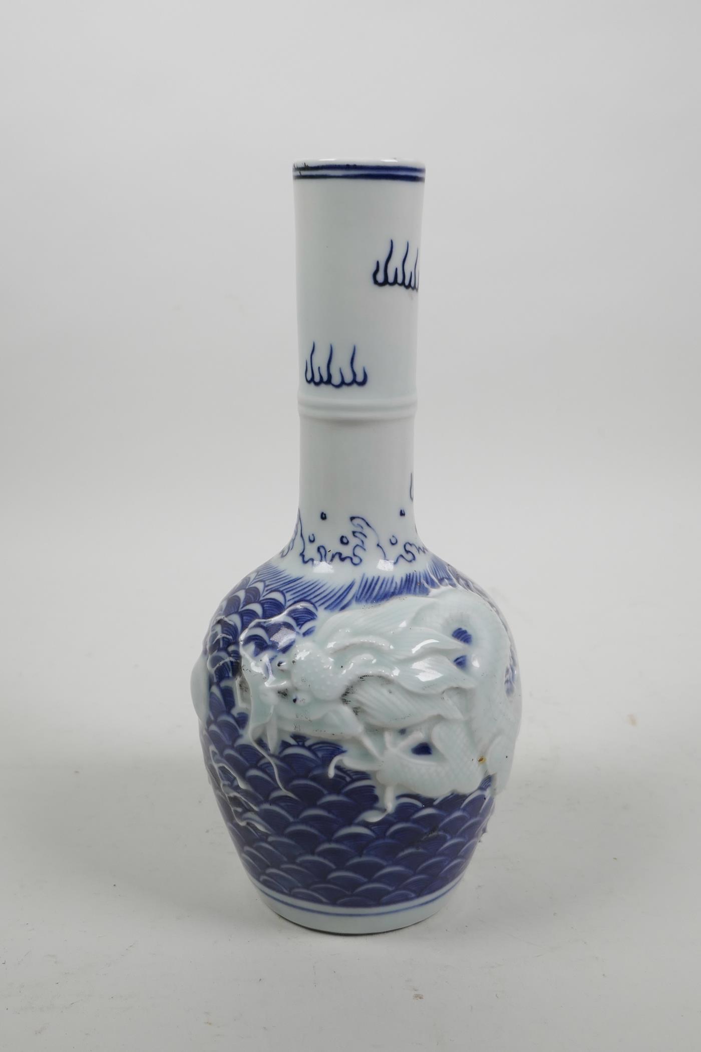 A Chinese blue and white porcelain bottle vase with raised decoration of a dragon chasing the