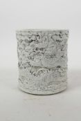 A Chinese moulded porcelain brush pot with raised decoration of dragons above water, impressed