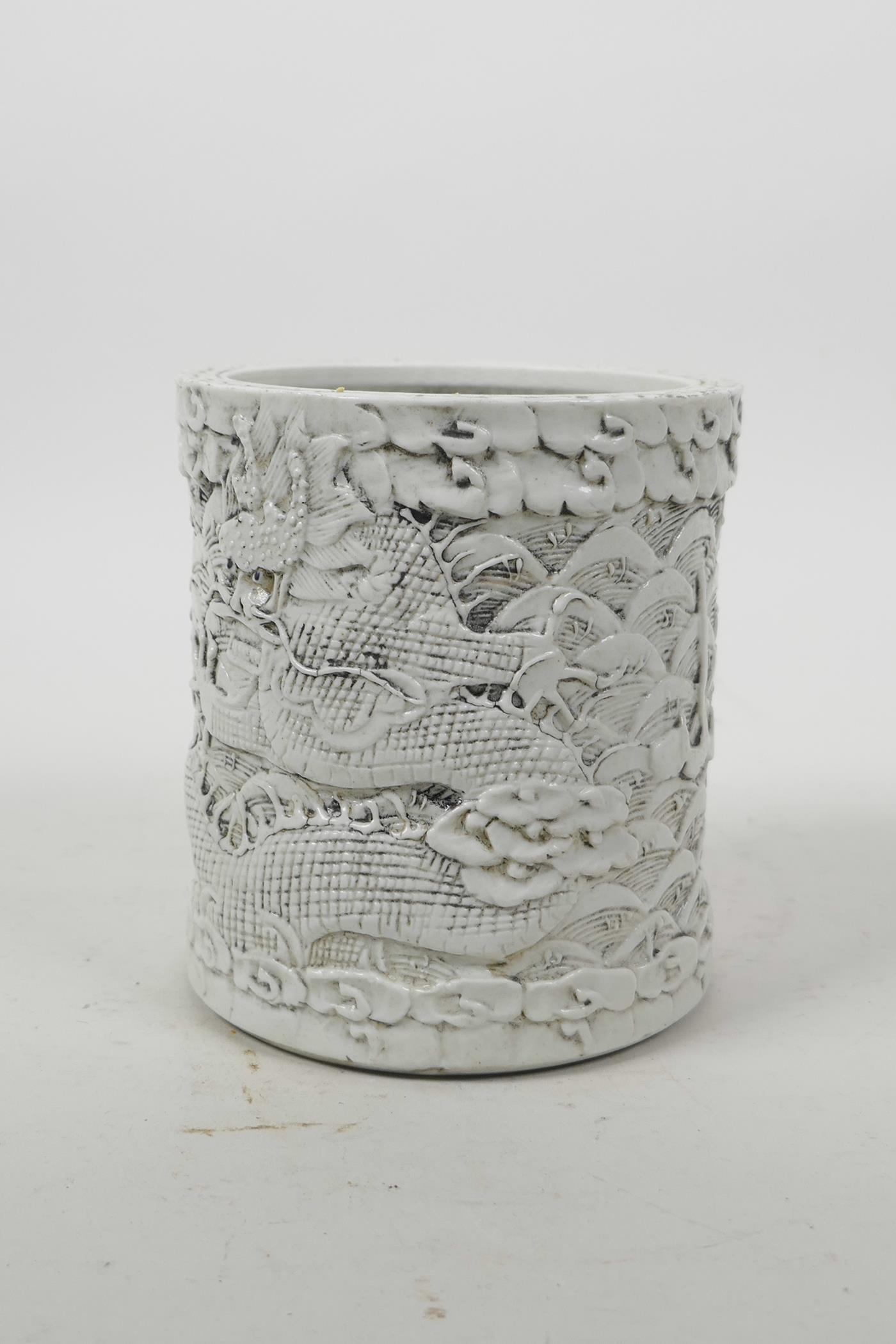 A Chinese moulded porcelain brush pot with raised decoration of dragons above water, impressed - Image 4 of 5
