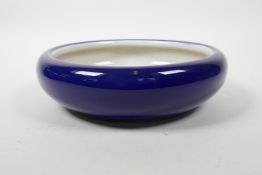 A Chinese powder blue glazed porcelain dish with a rolled rim, the interior with raised decoration