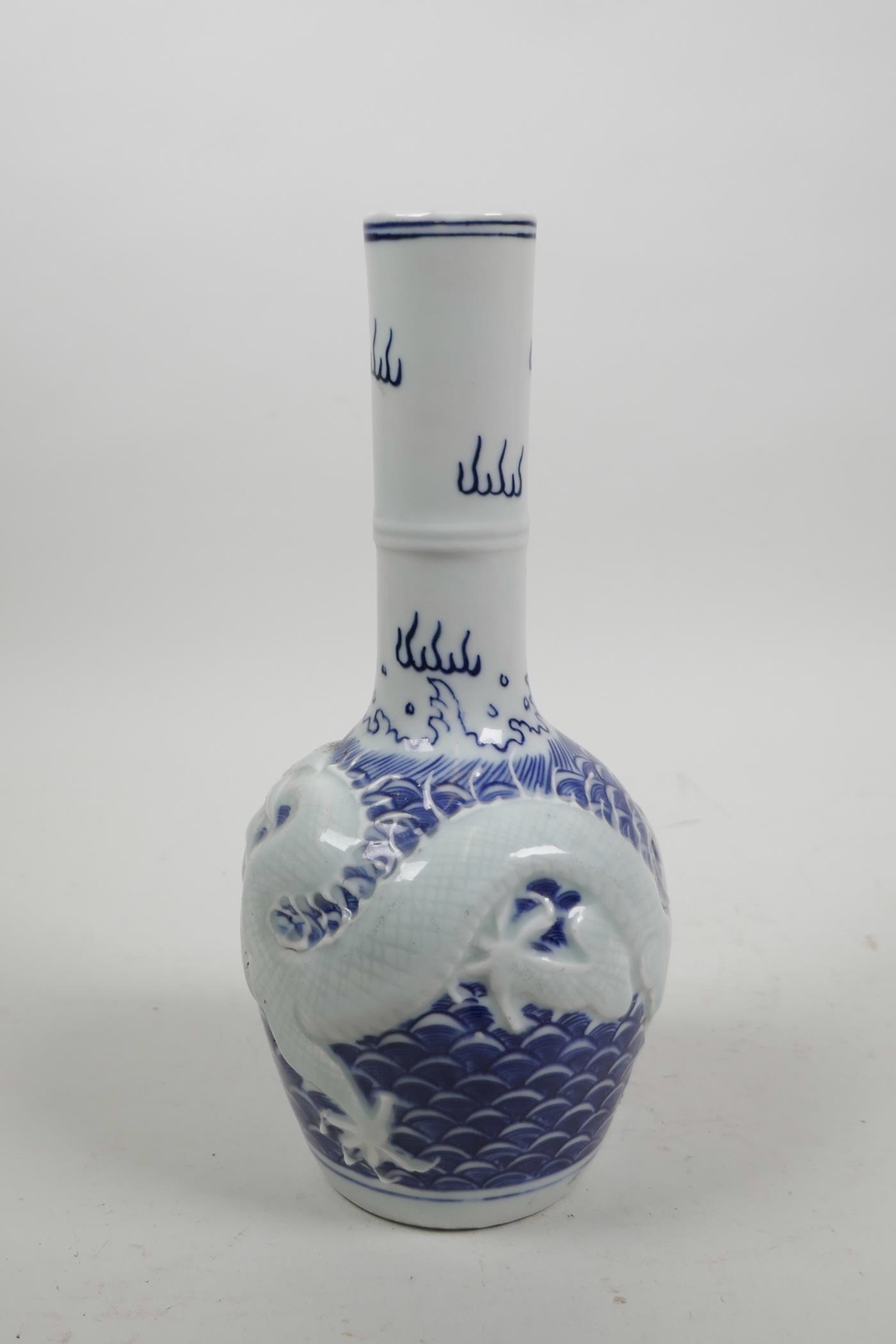 A Chinese blue and white porcelain bottle vase with raised decoration of a dragon chasing the - Image 2 of 5