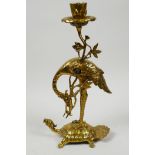 An Oriental polished brass candlestick cast as a stork on a mythical tortoise, 11" high