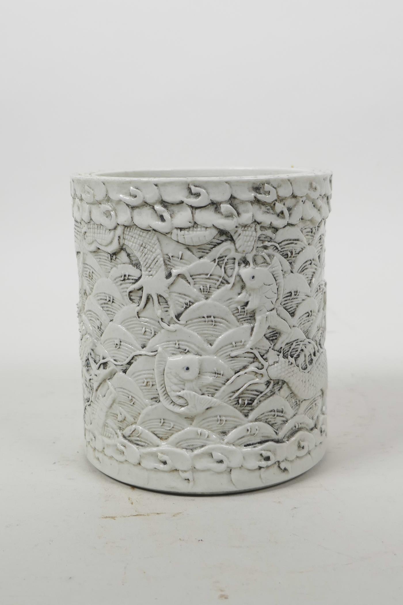 A Chinese moulded porcelain brush pot with raised decoration of dragons above water, impressed - Image 2 of 5