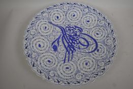 A Turkish Iznik pattern blue and white pottery charger decorated with script and floral scrolls,