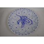 A Turkish Iznik pattern blue and white pottery charger decorated with script and floral scrolls,