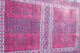 A Turkish hand woven wool carpet with traditional geometric designs on a red field, 60" x 83"