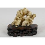 An early C20th Japanese carved ivory okimono figure of a sage being hugged by three boys, mounted on