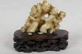 An early C20th Japanese carved ivory okimono figure of a sage being hugged by three boys, mounted on