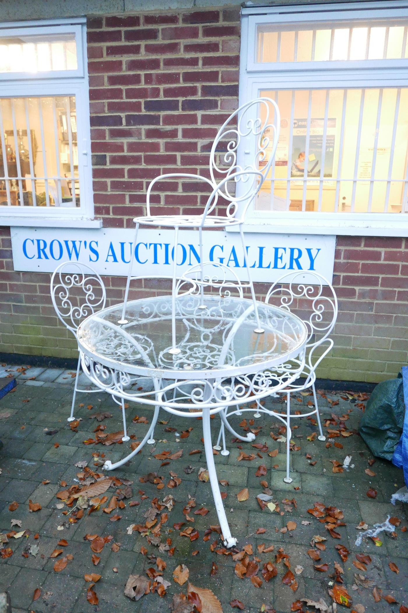 A white painted metal garden table and four chairs, the table with a glass top, 36" diameter, 30½"