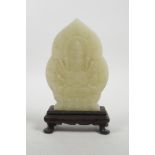 A Chinese celadon jade carving of a many faced deity on a hardwood stand, 7½" high