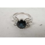 An 18ct white gold, sapphire and diamond ring, the central sapphire set between petal set