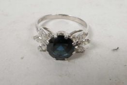 An 18ct white gold, sapphire and diamond ring, the central sapphire set between petal set