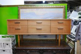 A mid C20th teak veneered side chest of six drawers, raised on tapering supports, 57" x 17" x 26"