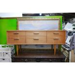 A mid C20th teak veneered side chest of six drawers, raised on tapering supports, 57" x 17" x 26"