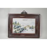 A Chinese famille verte porcelain panel depicting a riverside landscape, mounted in a hardwood