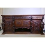 A large carved oak sideboard with three drawers divided by lion masks over cupboards, all