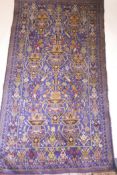 An antique Persian silk and wool carpet with vase decoration on a blue field, A/F, 78" x 43"