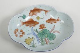 A Chinese petal shaped serving dish decorated with carp amongst water plants painted in bright