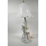 A Lladro porcelain table lamp in the form of two ballet dancers around a tree with milk glass shade,