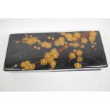 A Japanese black lacquer artist's box decorated with gilt and red prunus blossom containing a