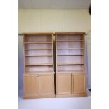 A pair of contemporary light oak veneered open bookcases with two cupboards below, in two