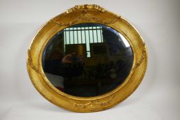 An oval gilt gesso mirror with reeded frame, surmounted by carved swags and a tied ribbon carving to