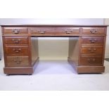 An early C20th nine drawer pedestal desk with inset tooled leather writing surface and brass drop