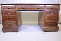 An early C20th nine drawer pedestal desk with inset tooled leather writing surface and brass drop