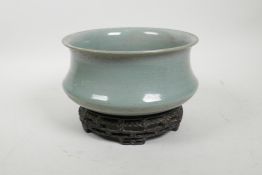 A Chinese Ru ware style celadon crackle glazed bowl on a carved hardwood stand, the base with an