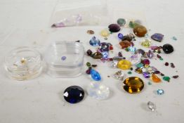 A collection of loose cut gemstones, including topaz, tourmaline, garnet and a variety of