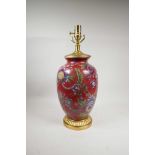 A Chinese polychrome porcelain vase with gilt wood mounts, decorated with Asiatic flowers on a red