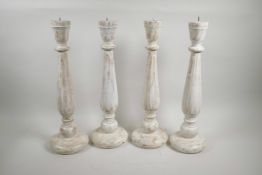 A set of four painted and distressed turned wood pricket candlesticks, 18" high