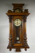 A late C19th Vienna wall clock, walnut, with enamel dial, Roman numerals and decorative pedestal