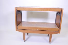 A mid C20th teak hostess trolley with cantilever action, with melamine top, raised on castors