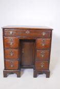 A Georgian oak kneehole desk of small proportions with a long drawer over six short drawers flanking