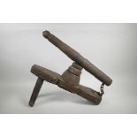 An Indian carved wood grinder, possibly for betel nut, 20" long, leg missing