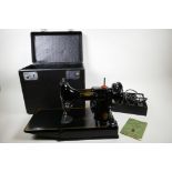An early 1950s Singer model 221k1 featherweight portable electric sewing machine, with original